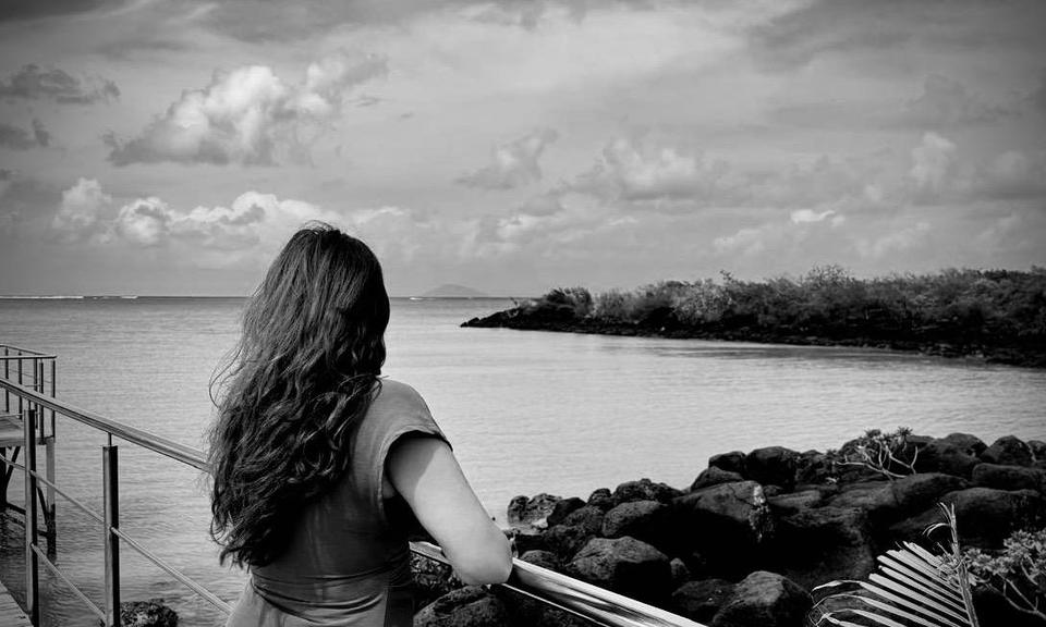 A woman standing at the water's edge, looking toward the horizon